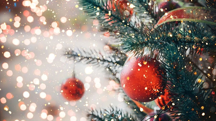 Närbild på en grangren där det hänger en röd julgranskula.