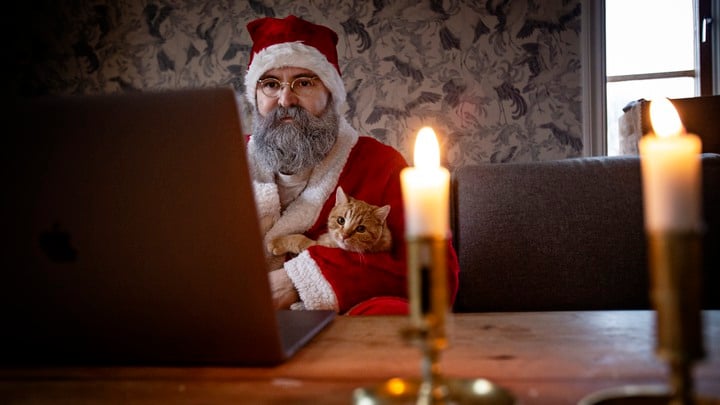 Tomten Tobias Guldstrand har sprayat skägget vitt och sitter redo vid datorn tillsammans med katten Findus.