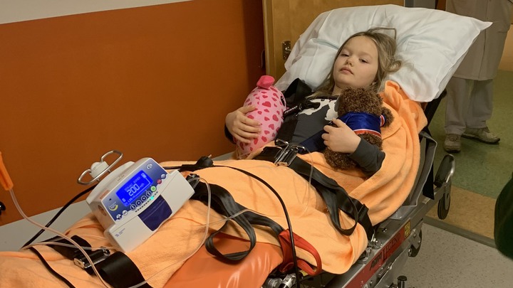 Alice ligger fastspänd på en sjukhusbår