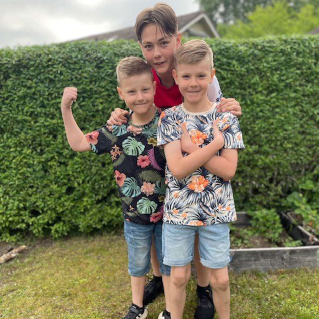 Dom tre bröderna står tätt tillsammans i en trädgård.