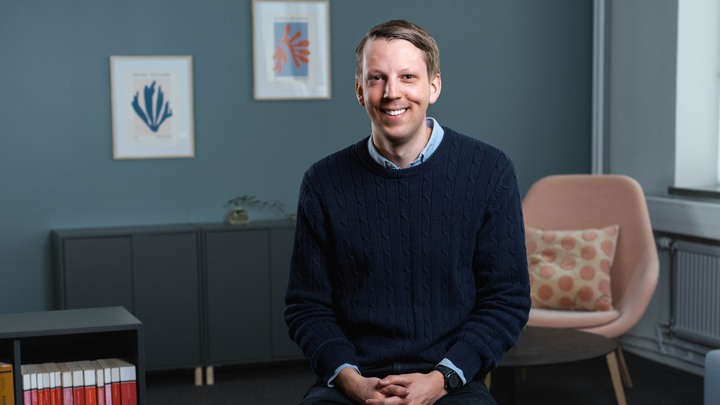 Ung man i kontorsmiljö som ler mot kameran