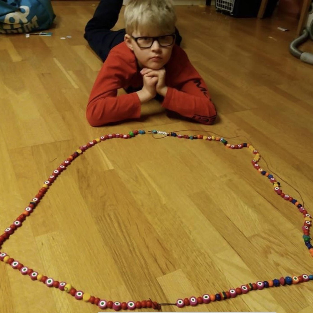Elvin ligger på mage på golvet, stöttad på sina armbågar och med sitt SuperSnöre framför sig