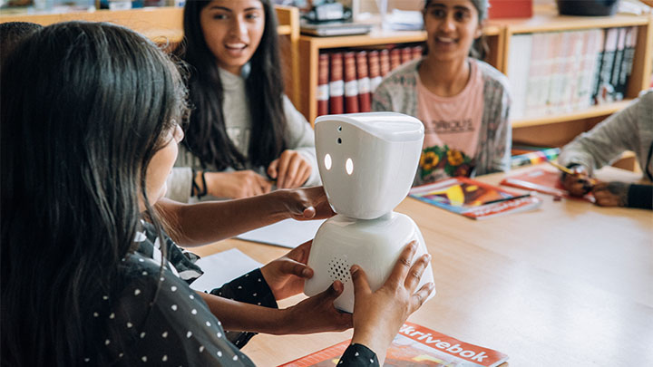En flicka håller i AV1-robot i skolan