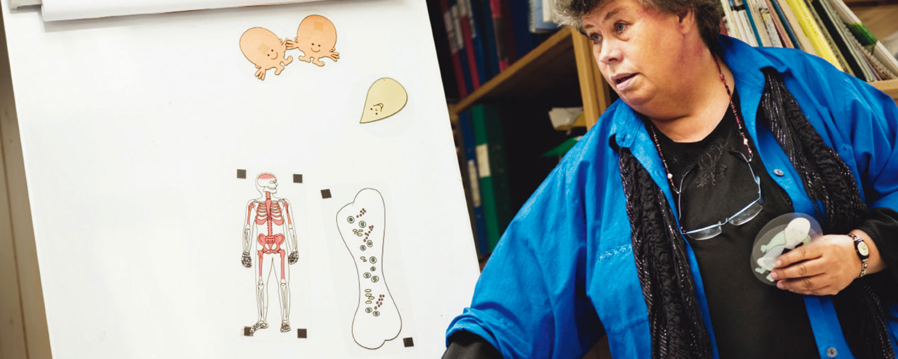 Eva klistrar utbildningsgubbar på tavlan.