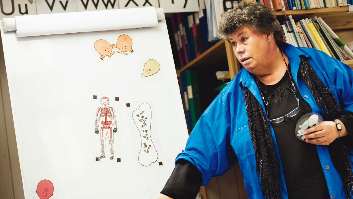 Eva klistrar utbildningsgubbar på tavlan.