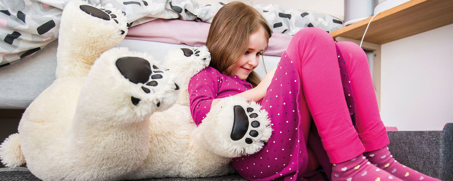 Alva sitter bredvid sitt gosedjur, isbjörnen.