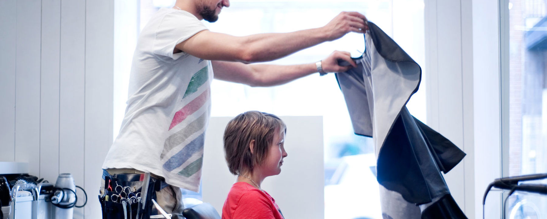 Frisörassistenten sätter skydd över Fannys kläder inför hennes frisörtid.