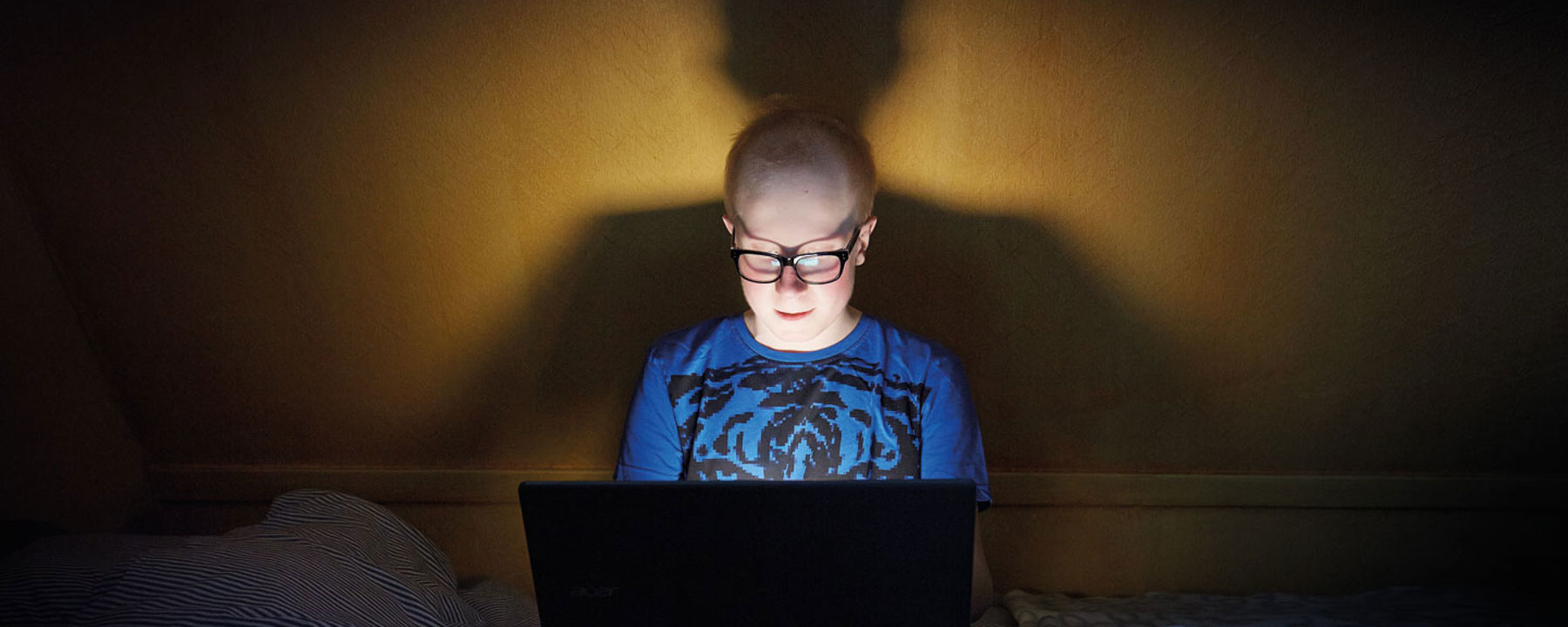 Max sitter med sin dator på sängen.