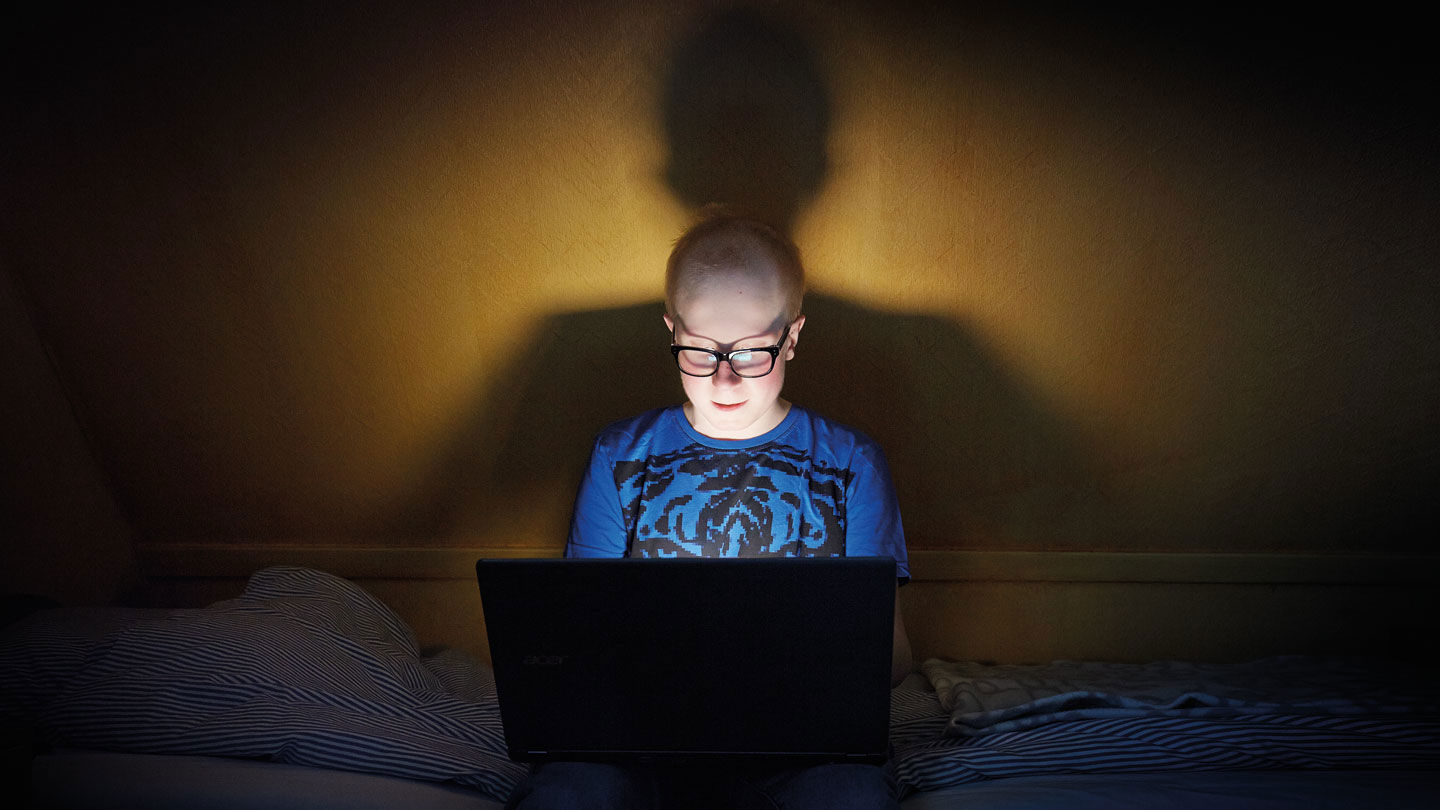 Max sitter med sin dator på sängen.