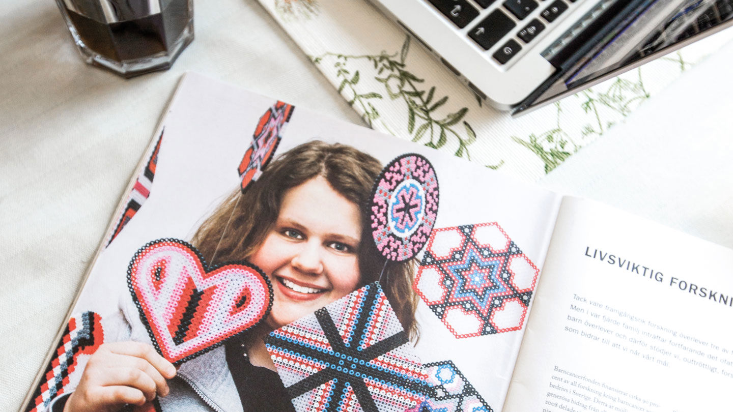 En tidsskrift ligger öppen på ett bord. Ellinor med sina pärlplattskreationer är med på bilden tryckt i uppslaget.