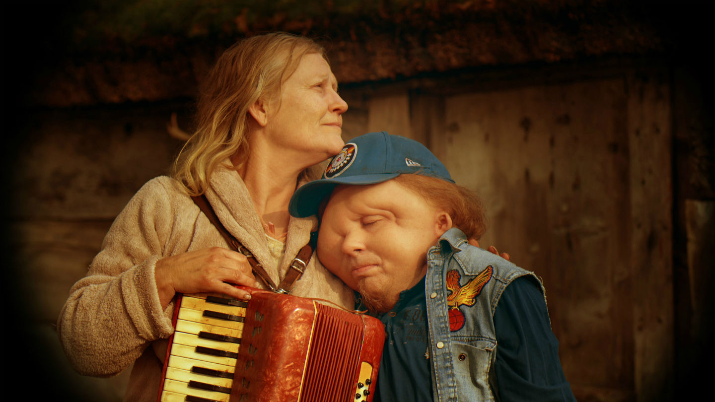 Stillbild från filmen Jätten. Christian Andréns karaktär lutar huvudet mot en annan karaktär.