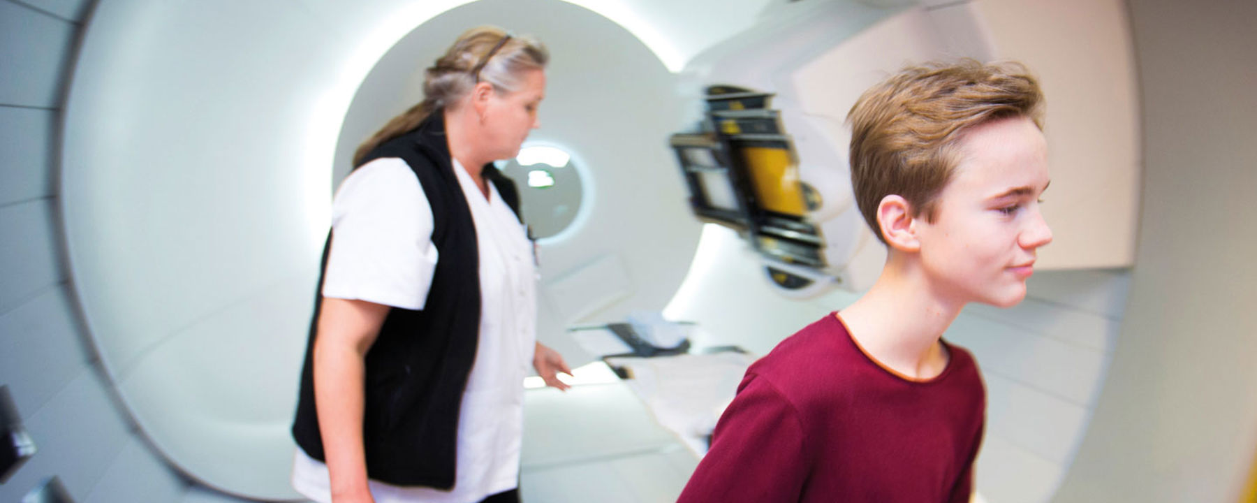 Joel står framför strålningsmaskinen på sjukhuset.