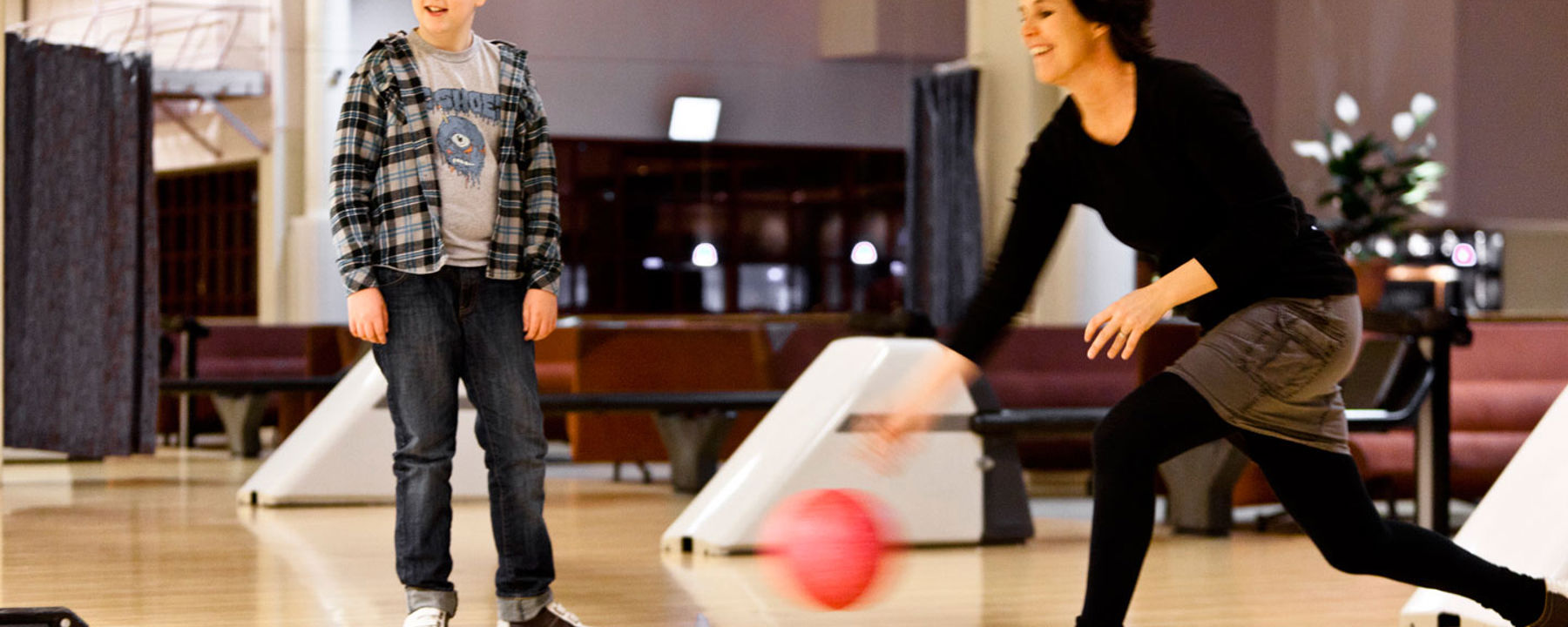 Eva slänger iväg ett bowlingklot medan Simon tittar på.