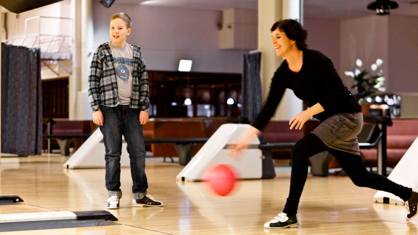 Eva slänger iväg ett bowlingklot medan Simon tittar på.