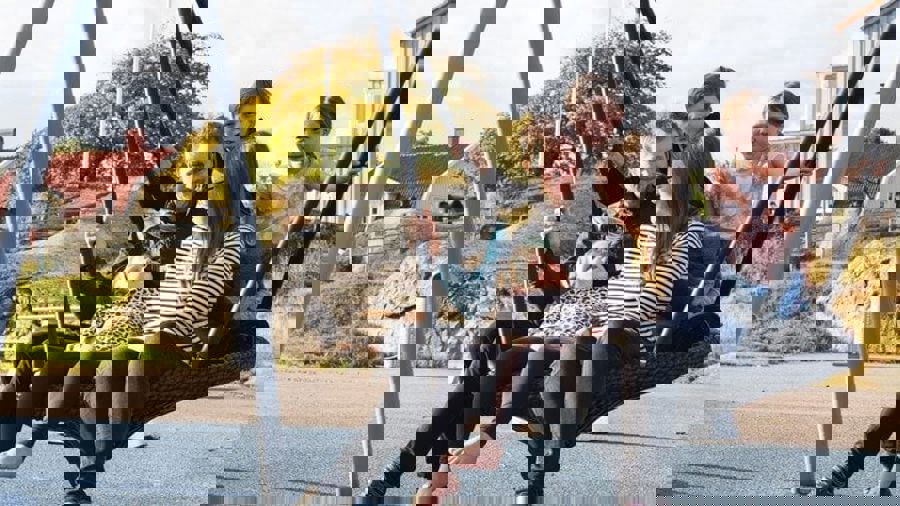 Fem personer i en stor rund gunga. I bakgrunden skymtar klippor och hus.