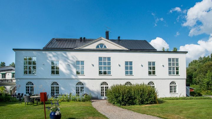 Vit hotellbyggnad med gräsmatta framför.