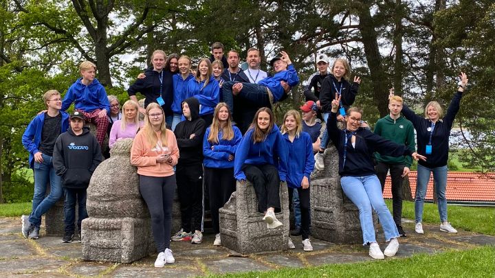 gruppbild ungdomar på gräsmatta och stenar