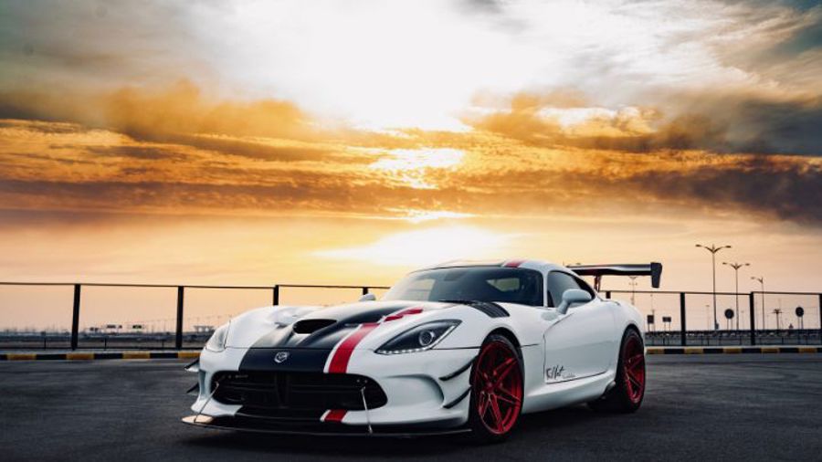 Parkerad vit sportbil med vacker himmel i bakgrunden.