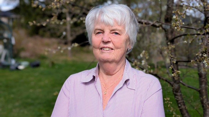 En kvinna som står framför ett träd.