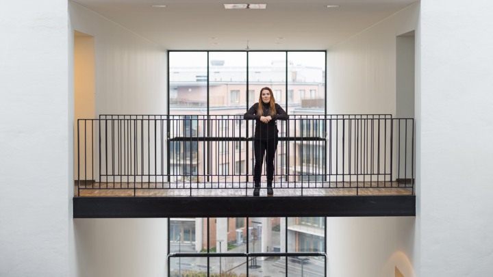 En kvinna står på en balkong bredvid ett fönster